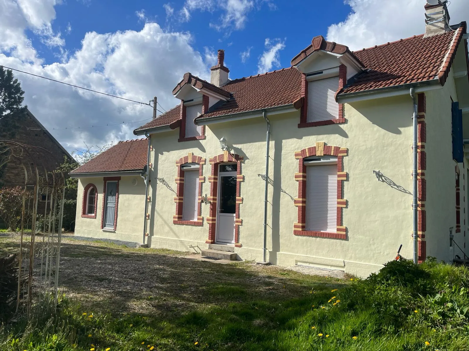 Façade rénovée crème avec encadrements rouge brique, toiture en tuiles