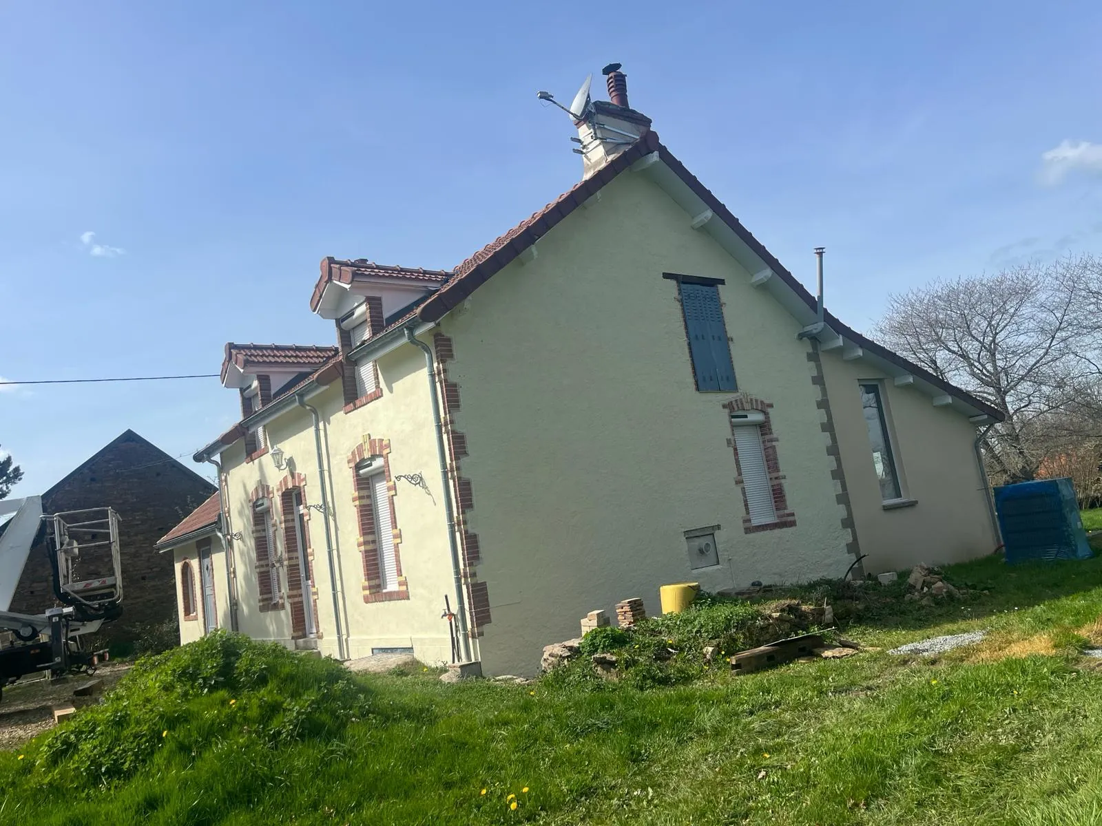 Façade rénovée couleur crème avec encadrements de fenêtres rouge brique et toiture en tuiles